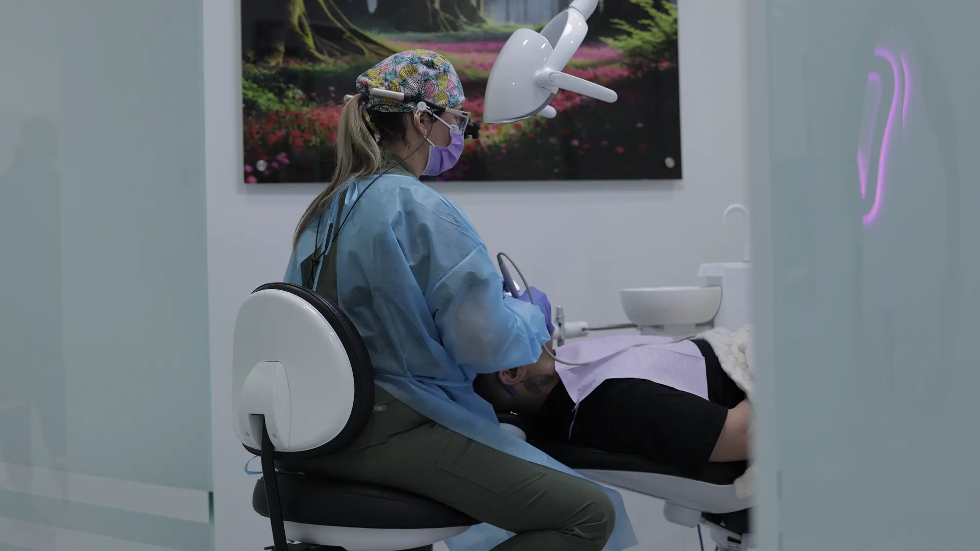 A dental professional caring for a patient in a treatment room.