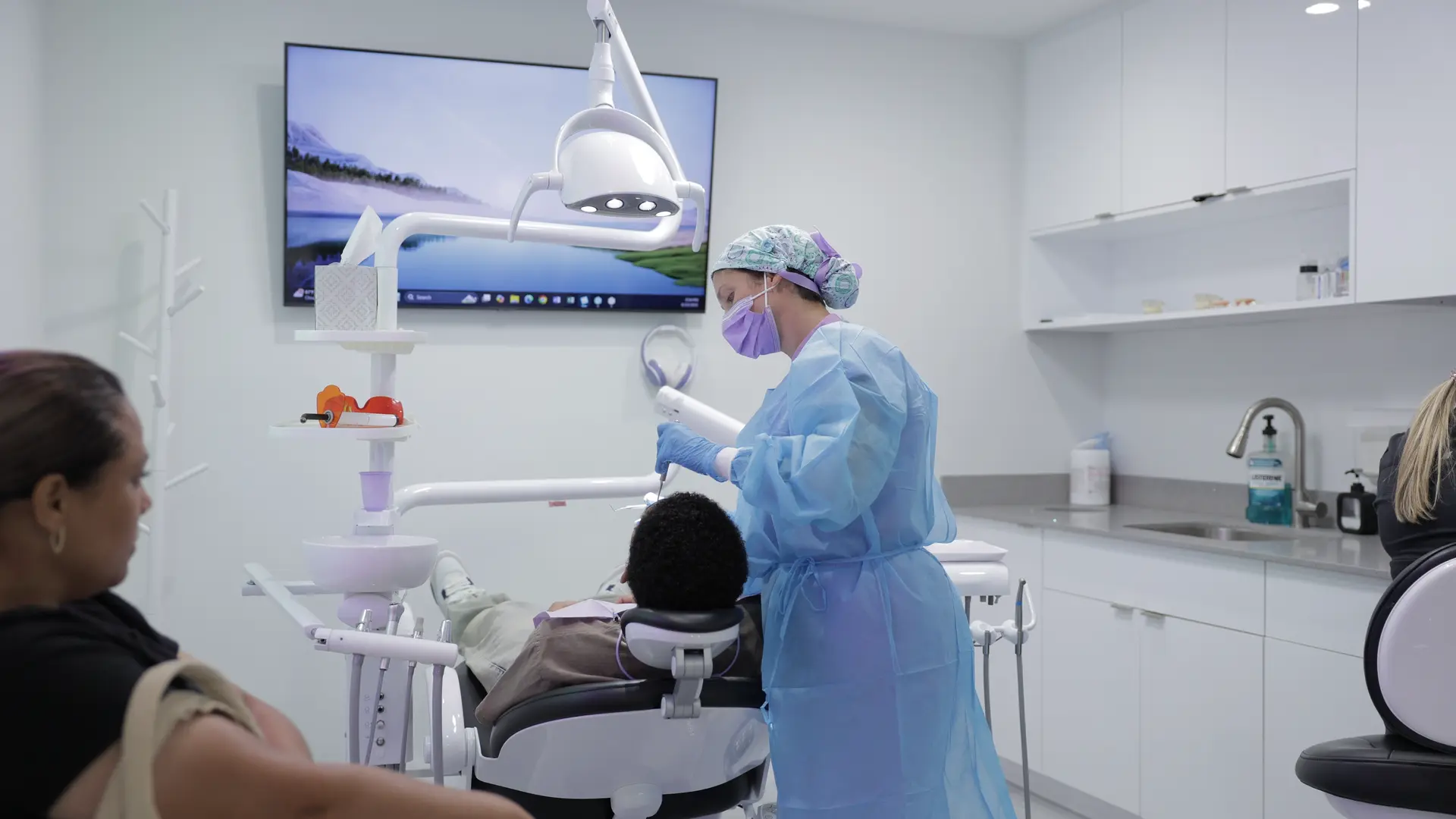 A dental professional examining a patient beneath an overhead dental light.