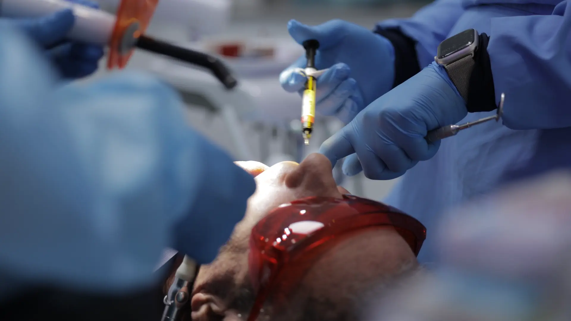 Close-up of a patient receiving dental care while wearing protective glasses.
