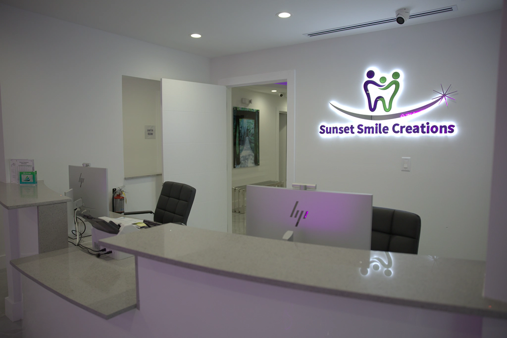 Reception desk with illuminated signage at the Sunset Smile Creations Calle 8 office.